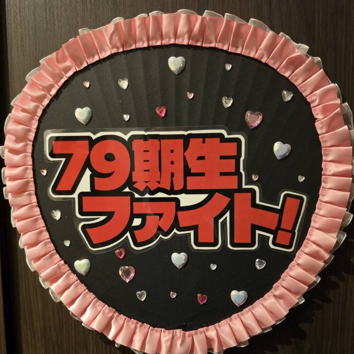 発表会うちわ 制作実例：「79期生ファイト！」（学年応援。ピンクのプリーツ縁×ハートストーン）